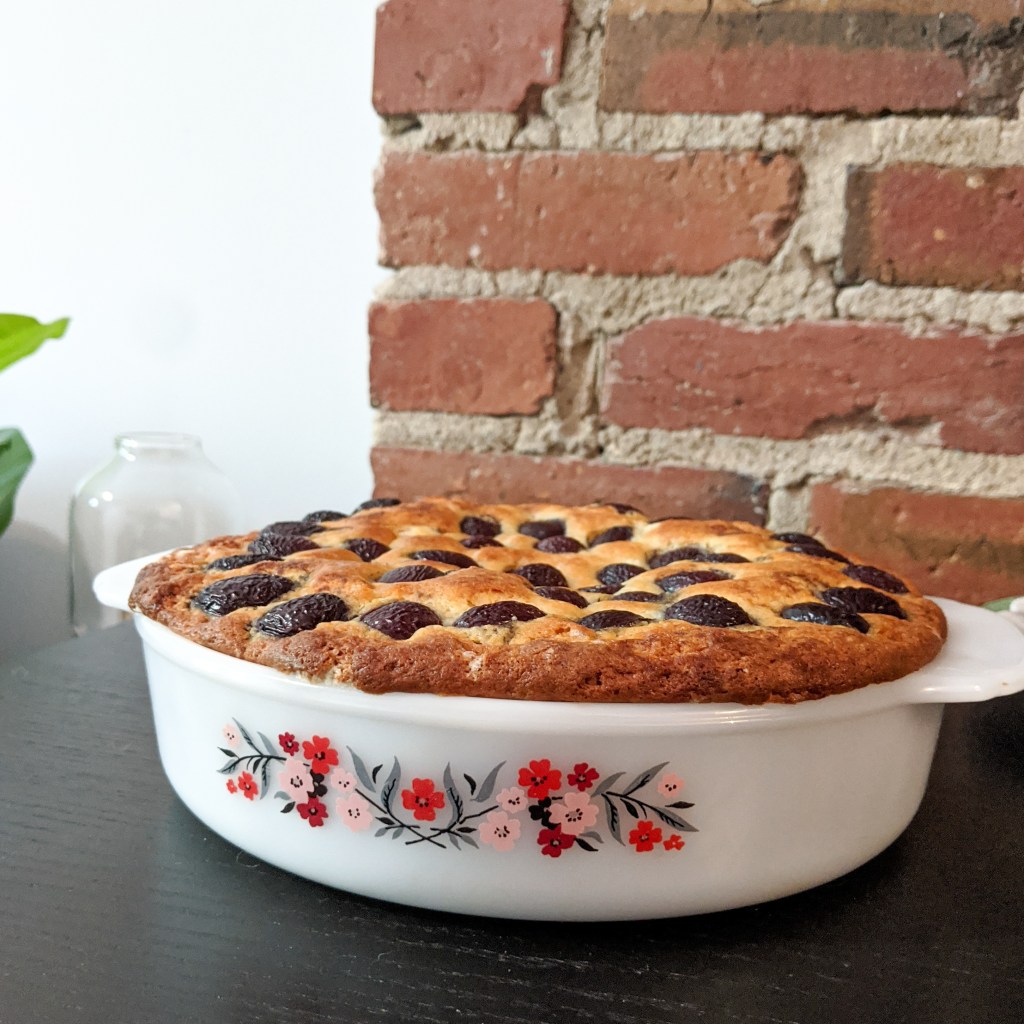 A cake with cherries pressed in the top baked in a flowery Pyrex dish