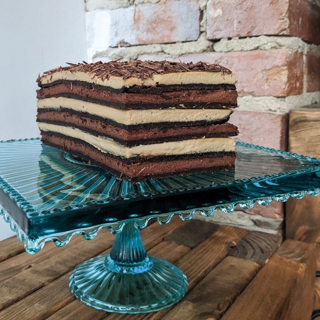 A cake with thin layers of chocolate cookie, chocolate cheesecake, and espresso cheesecake