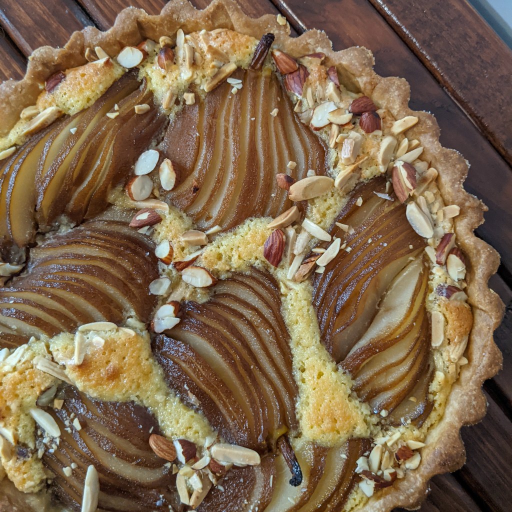 Top-down image of an almond tart with whole sliced pears baked into it
