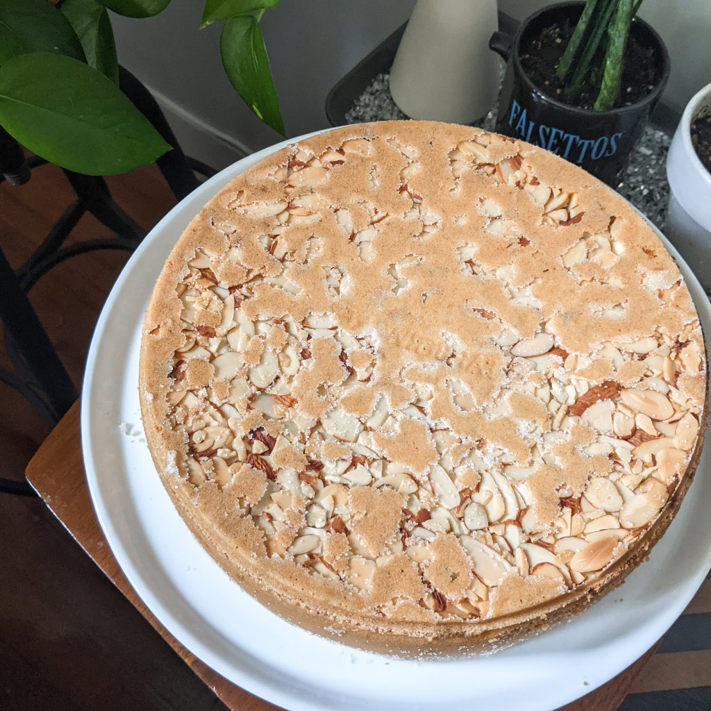 A top-down view of an almond-topped cake on a stand.