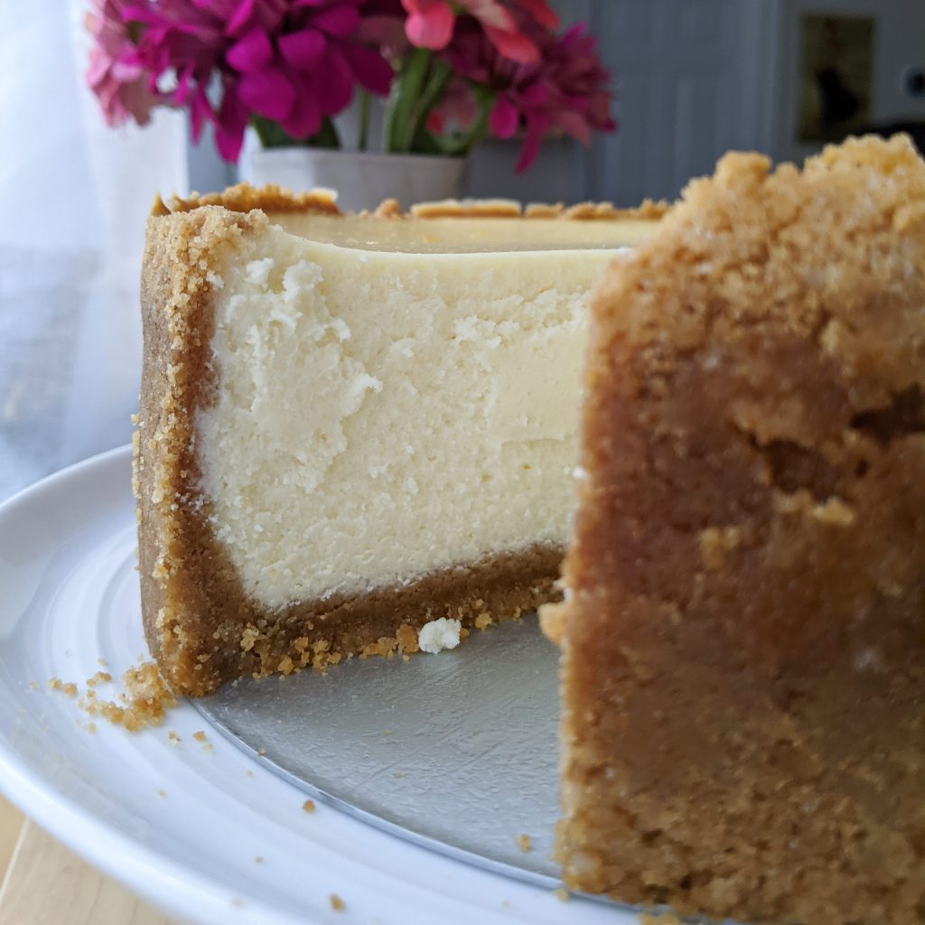 A close-up of tall cheesecake with a slice cut out