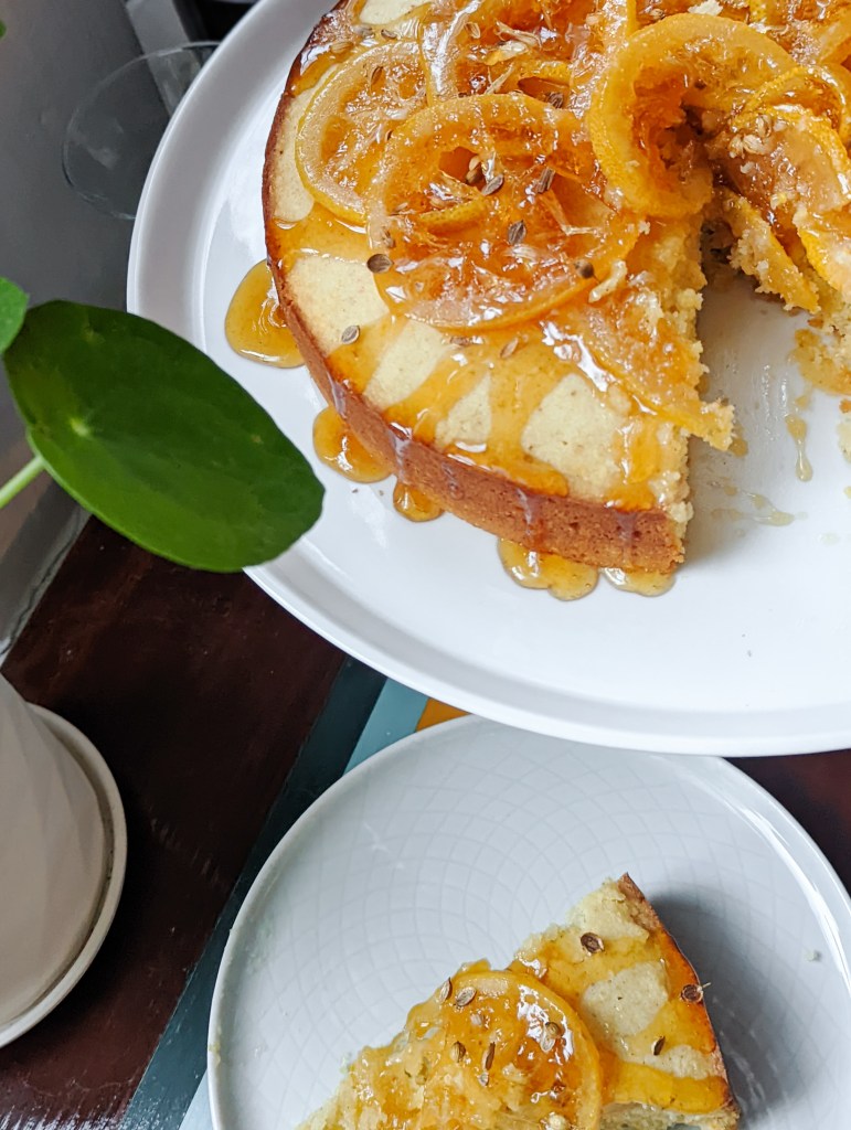 A lemon-covered cake with a slice removed and resting on a plate.