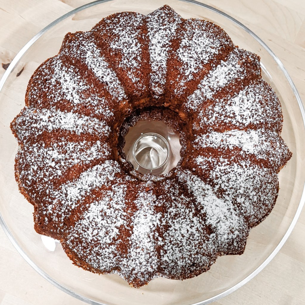A bundt cake lightly dusted with powdered sugar, seen from the top down